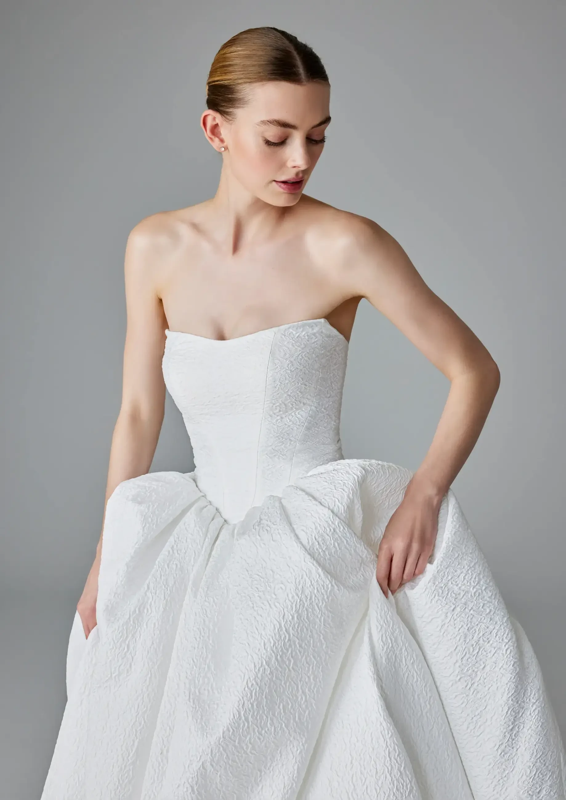 A model wearing a strapless white gown with a full skirt.