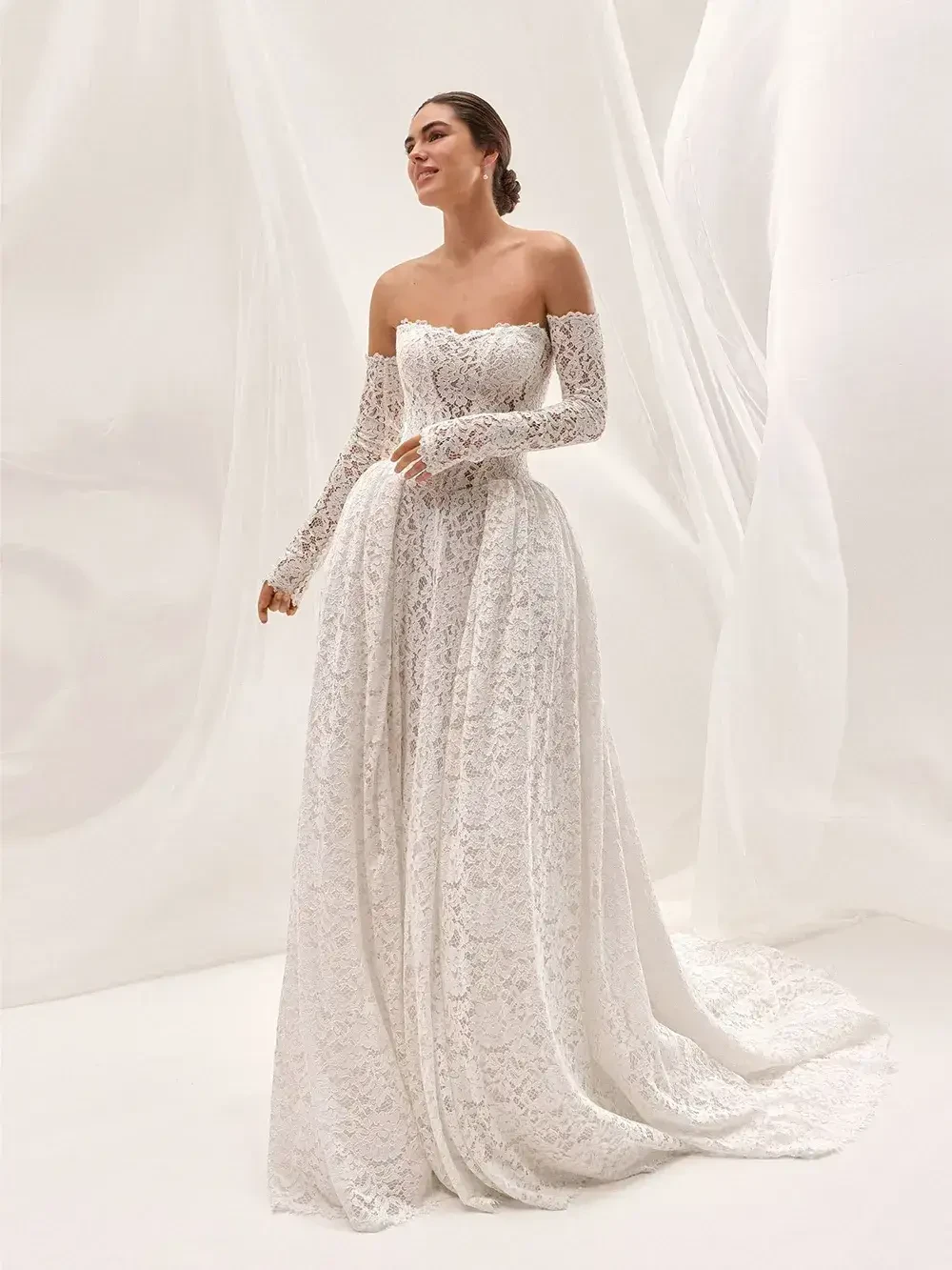 model is wearing an off the shoulder long sleeve lace bridal gown