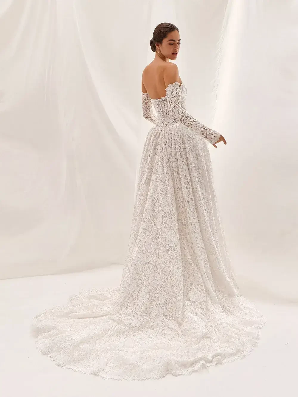 model is wearing an off the shoulder long sleeve lace bridal gown